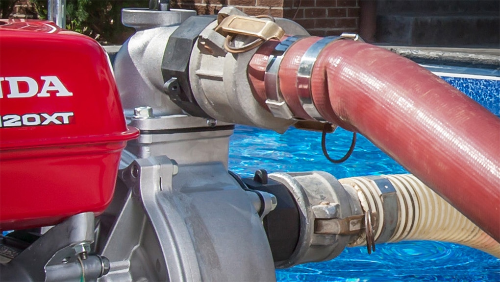 Close up of pump with hose attachments with pool in background
