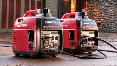 Deux génératrices Honda posées côte à côte sur la terrasse d’une belle maison résidentielle.