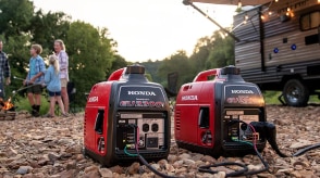 Two Honda generators are outdoors powering a recreational vehicle.  