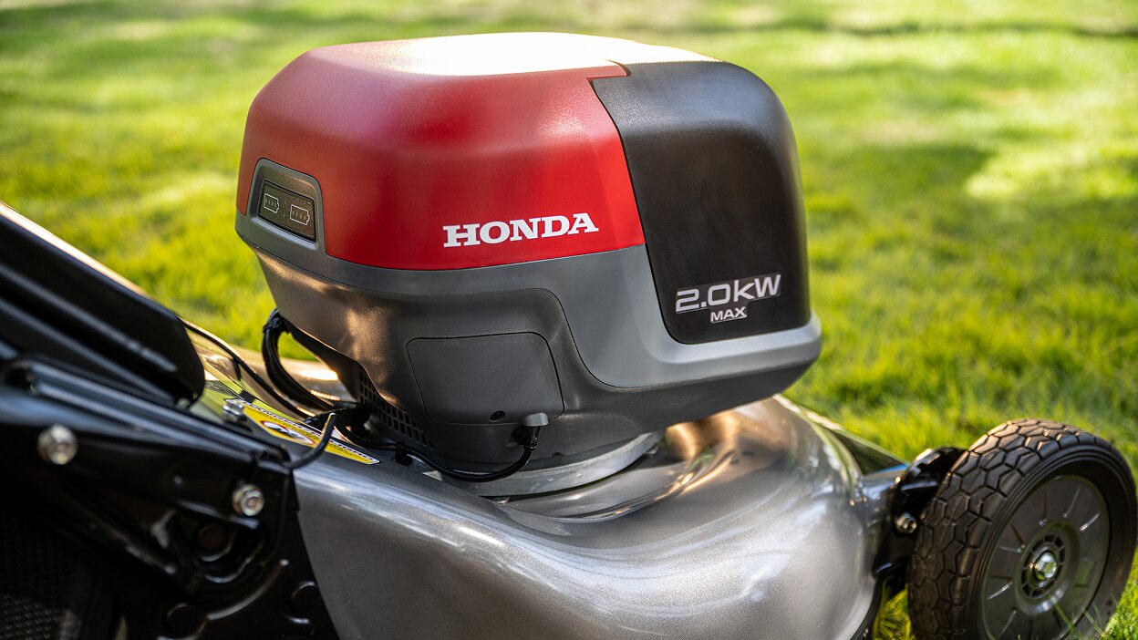 Gros plan de trois quart arrière droite du compartiment à batterie de la tondeuse à gazon à batterie. 