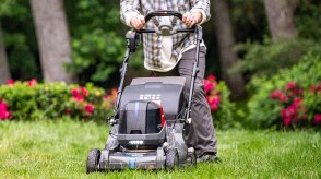 Personne poussant une tondeuse à batterie pour tondre la pelouse.