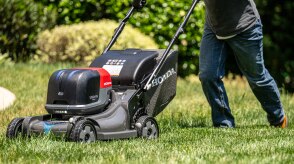 Une personne poussant une tondeuse à gazon à batterie Honda en train de tondre la pelouse. 
