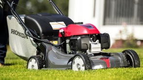 Gros plan d’une tondeuse poussée Honda utilisée à l’extérieur.  