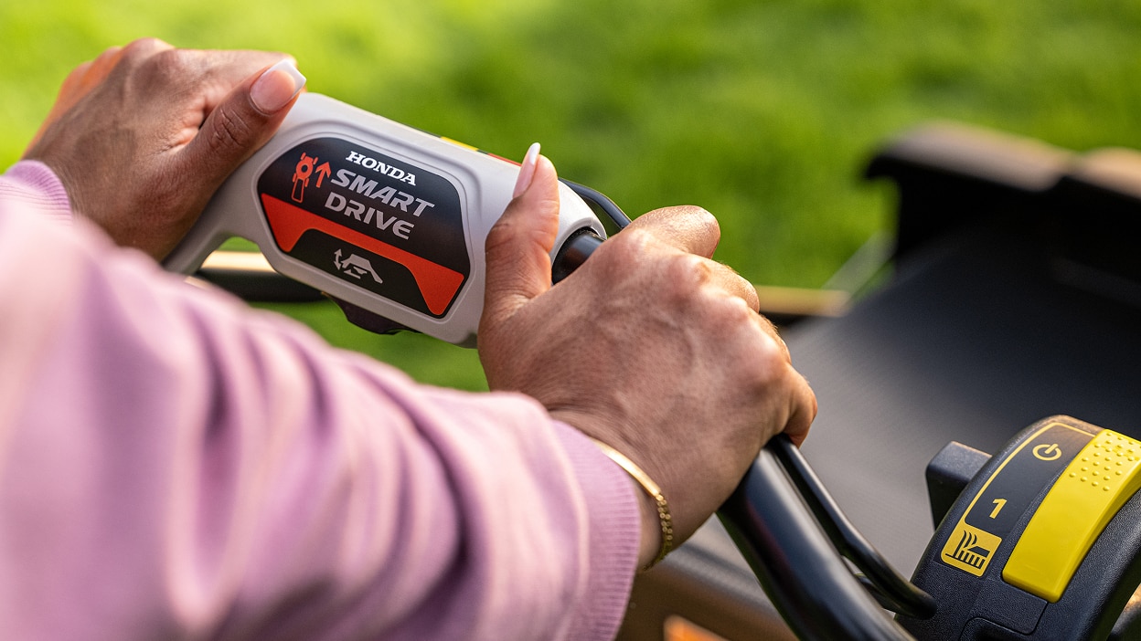 Close up of a person's hands holding the battery lawn mower handle.