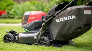 Vue de trois-quart arrière d'une tondeuse à batterie tondant la pelouse. 