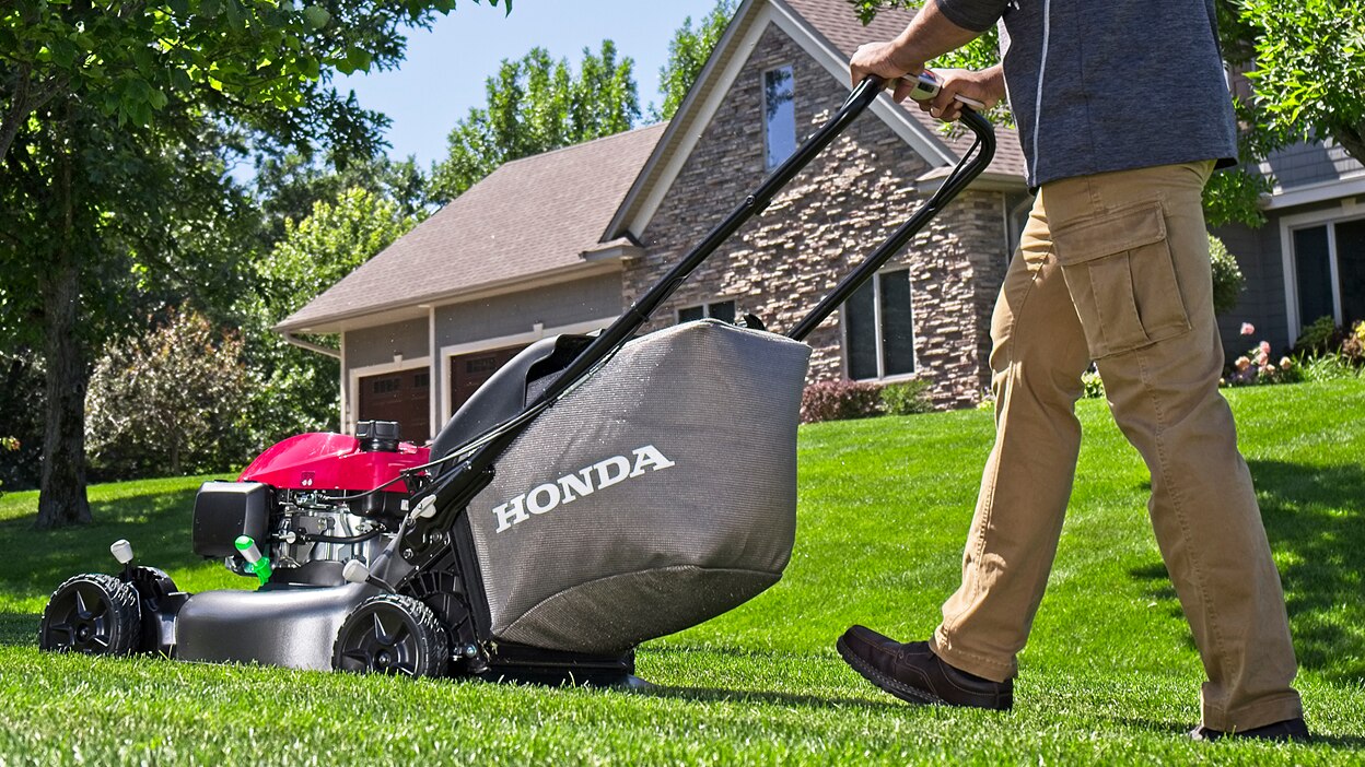 Person mowing lawn going left. House in background.