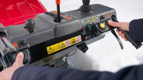 Closeup of hands holding the grip handles and using thumbs to push buttons, showcasing the convenient design of the handlebar-mounted console.  