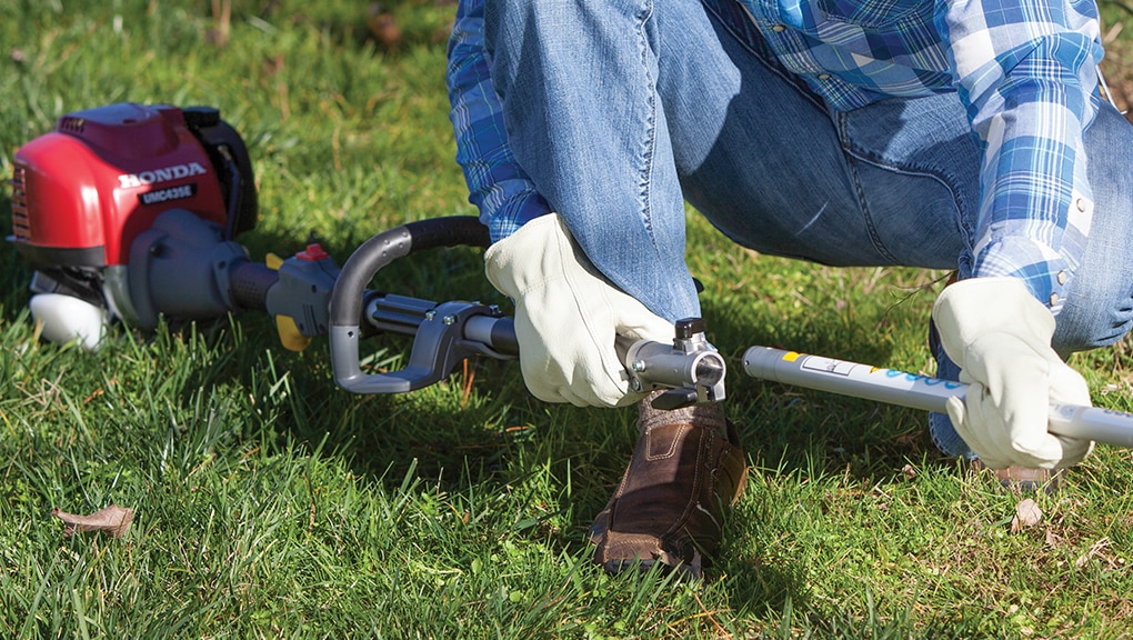 Close up of man in protective gear holding trimmer